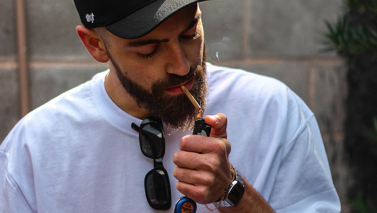 A young man lighting up a marijuana joint
