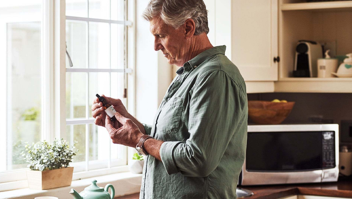 Medical Cannabis May Improve Symptoms of Depression and Anxiety: An elderly man holding a CBD bottle in his hands Medical Cannabis May Improve Symptoms of Depression and Anxiety: An elderly man holding a CBD bottle in his hands