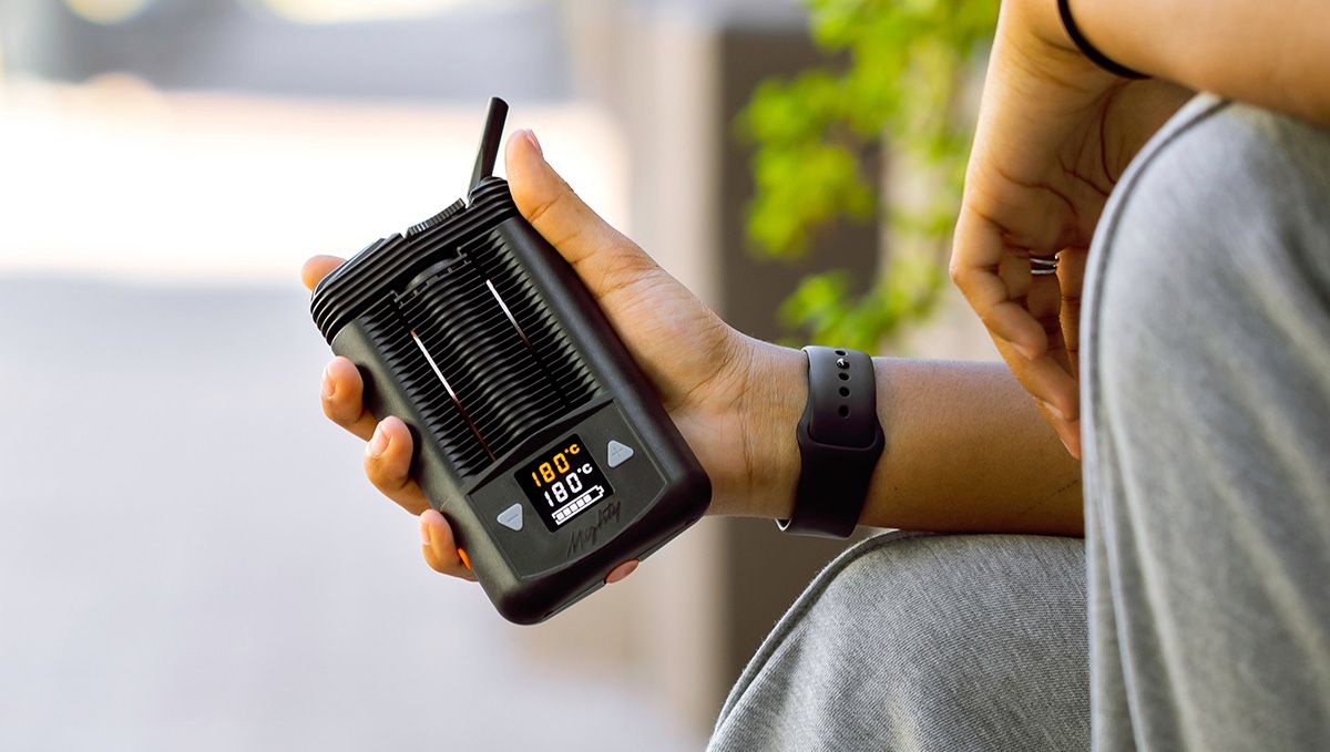 Tips For Choosing Best Weed Pens To Puff In: A closeup of young man's hands holding a big portable vaporizer with temperature settings Tips For Choosing Best Weed Pens To Puff In: A closeup of young man's hands holding a big portable vaporizer with temperature settings