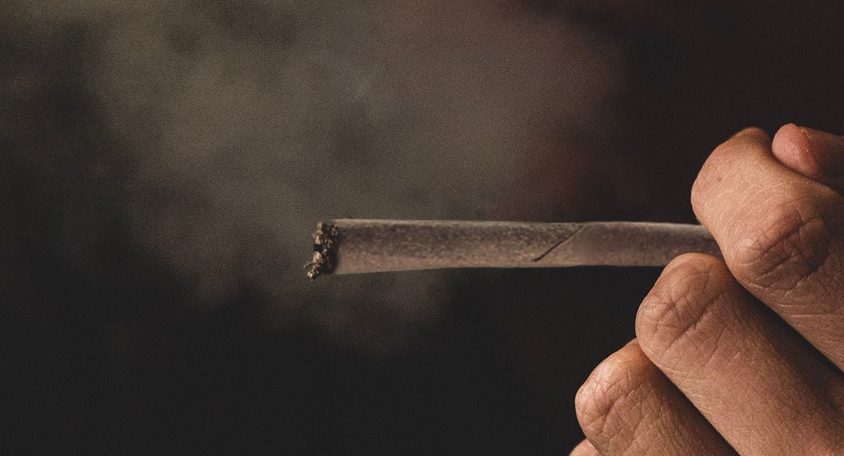 A closeup of a man's hand as he's holding a burning blunt