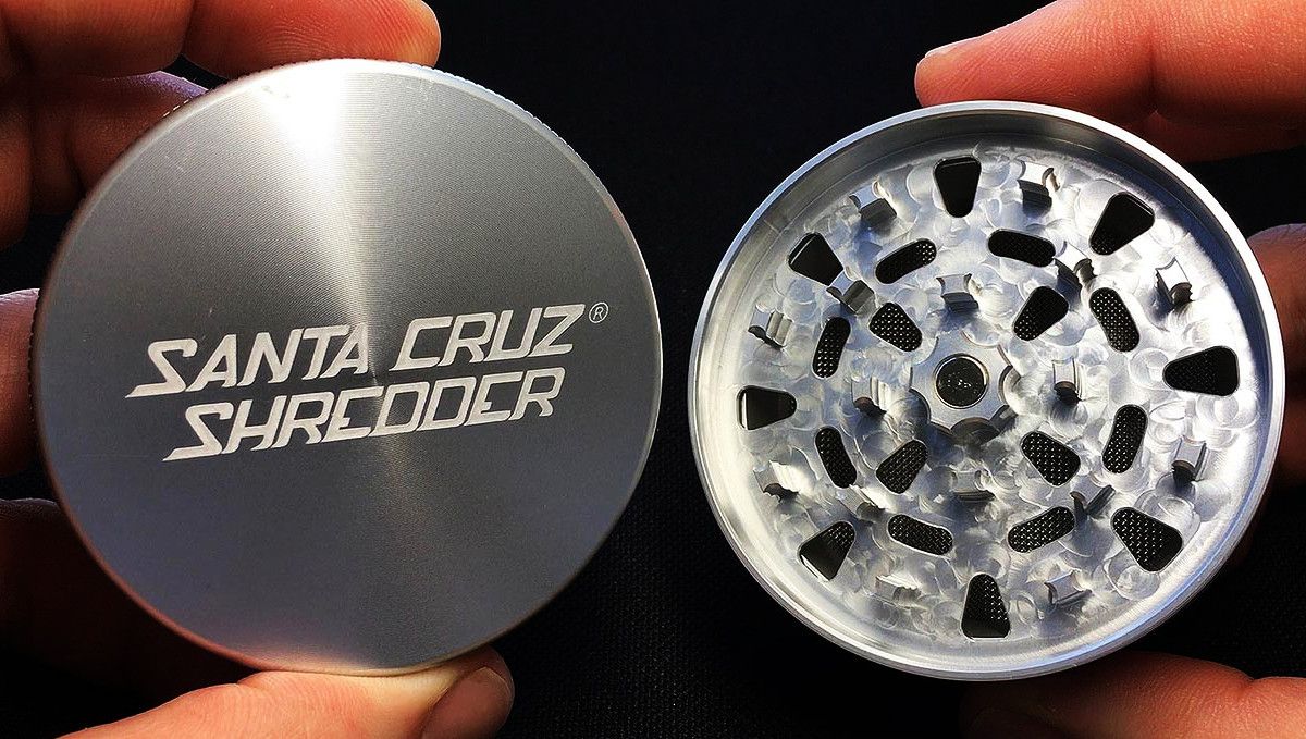 15 Best Weed Grinders to Buy in 2022: A closeup of man's hands holding two sections of a Santa Cruz Shredder