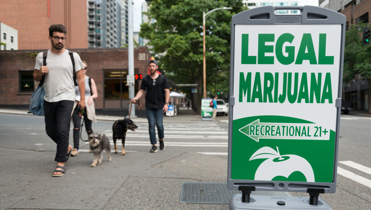 People walking their dogs and looking at a legal-marijuana sign People walking their dogs and looking at a legal-marijuana sign